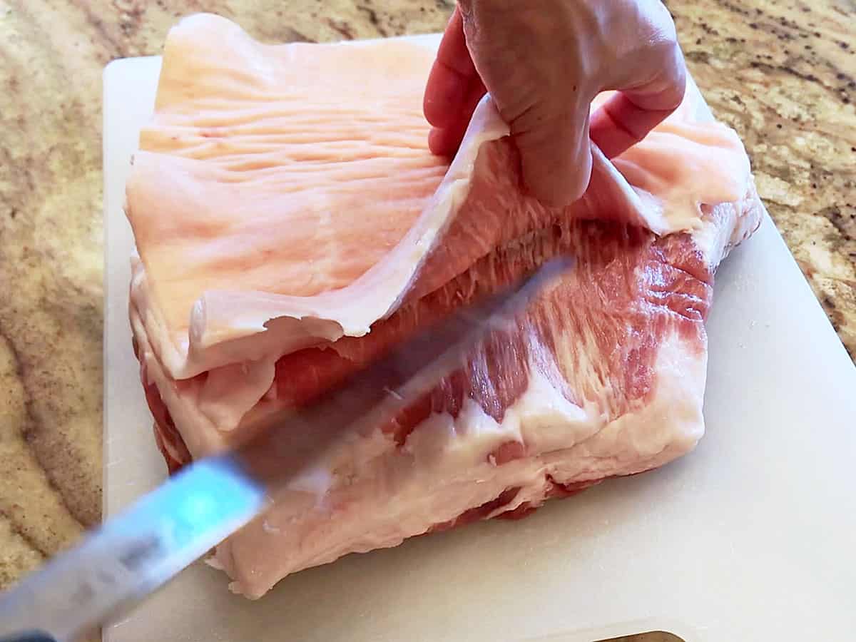 Removing pork belly skin with a chef's knife.