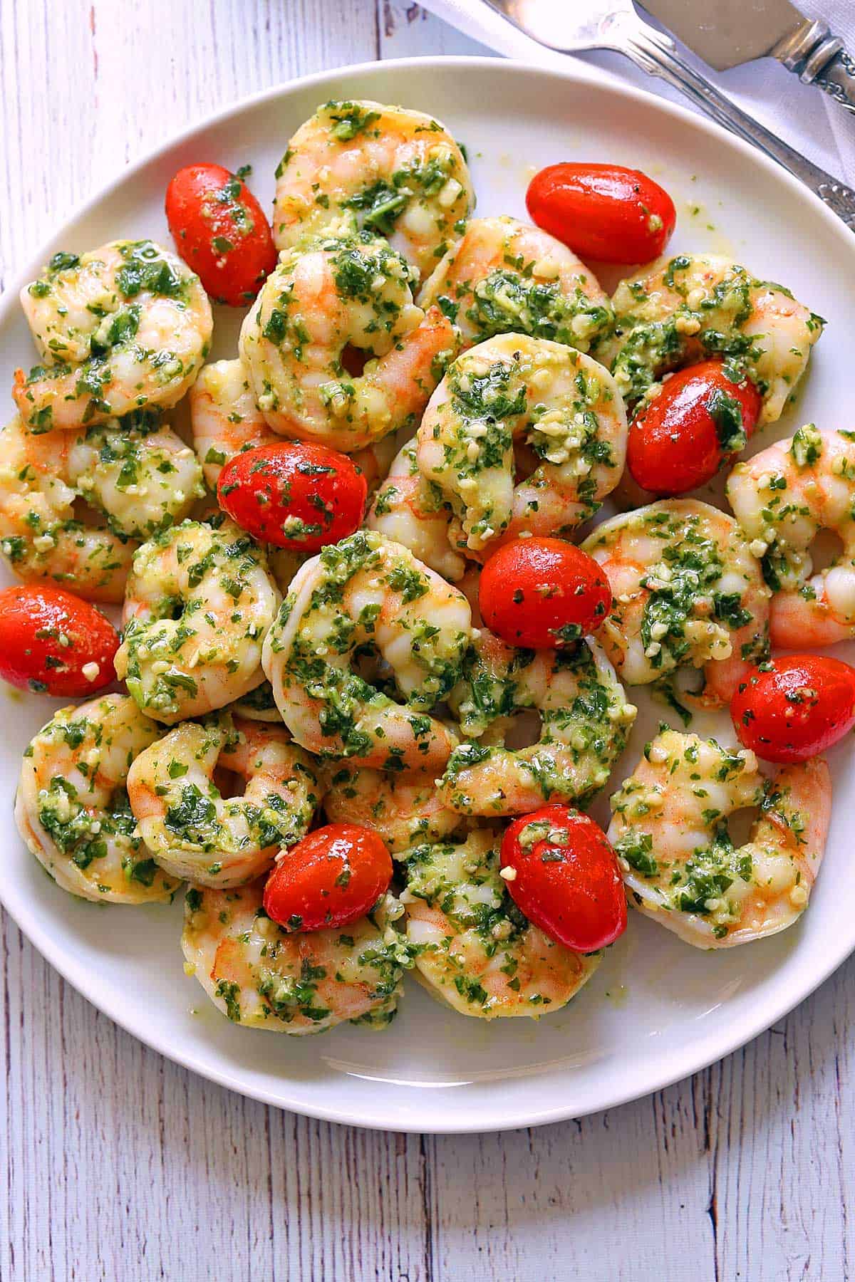 Pesto shrimp served on a white plate.