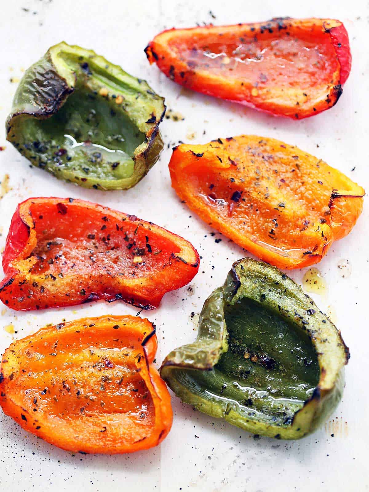 Roasted peppers on a parchment-lined baking sheet.