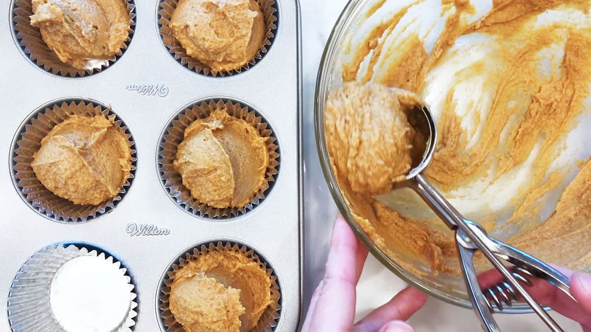 Dividing the mixture between muffin cups.