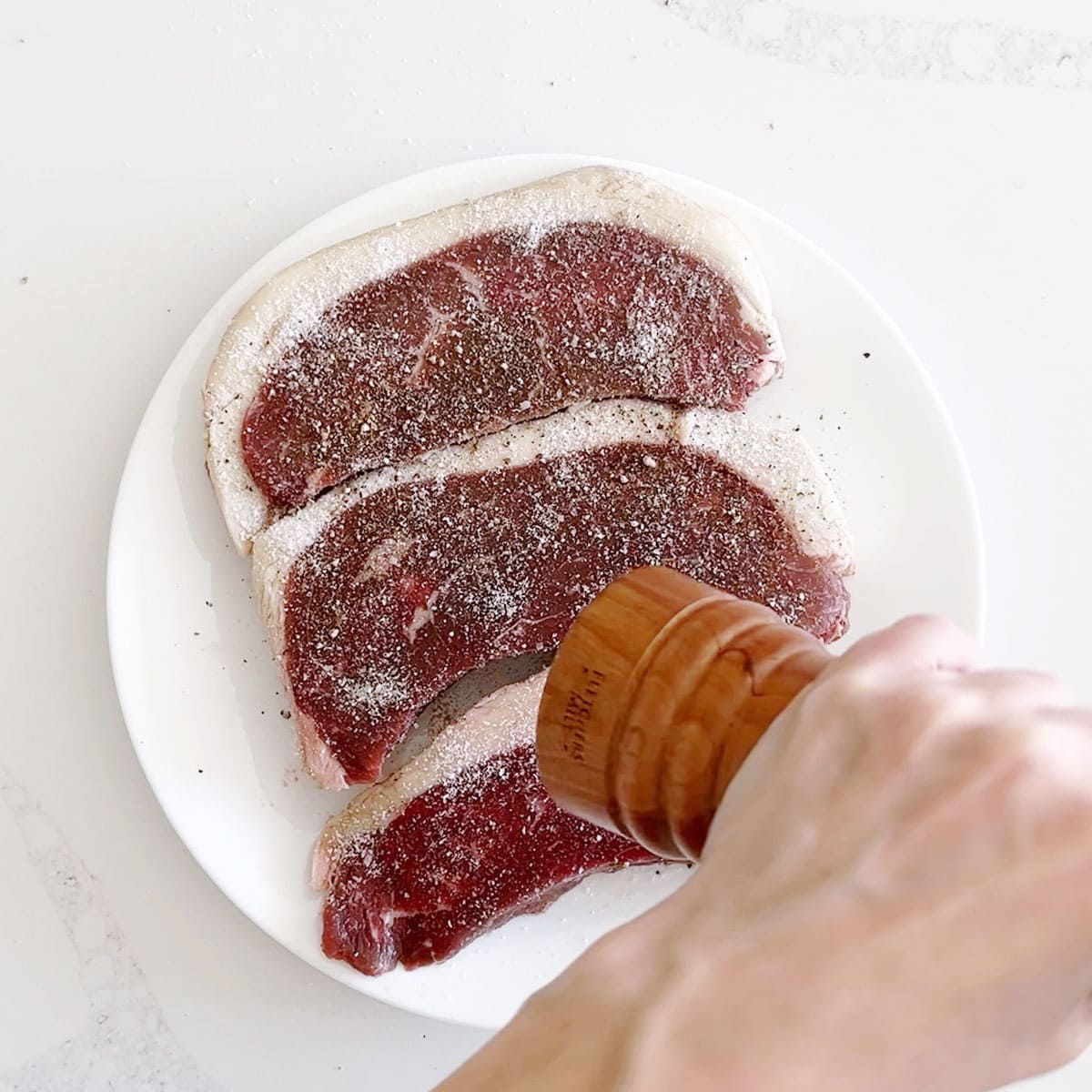 Seasoning picanha steaks with salt and pepper.