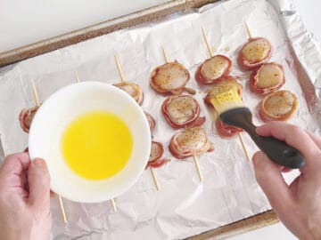 Brushing the scallops with melted butter.