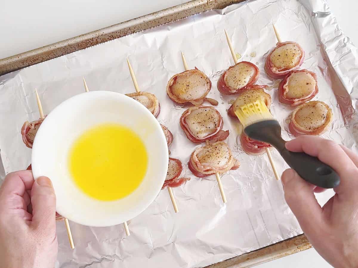 Brushing the scallops with melted butter.