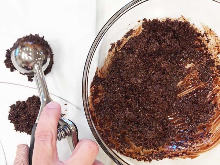 Dropping mounds of the coconut-chocolate mixture onto wax paper.