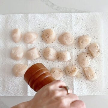 Seasoning the scallops.