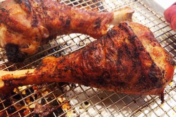 Fully cooked turkey legs on a baking sheet.