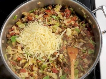 Adding shredded cheese to the skillet.