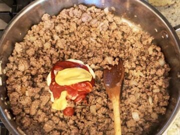 Stirring mayo, mustard, and ketchup into the beef mixture.