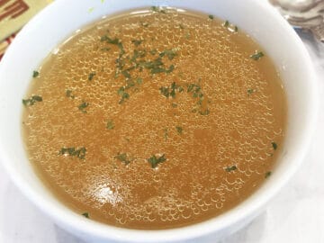 Chicken broth is served in a bowl.