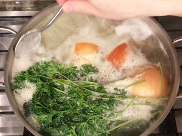 Skimming foam from the boiling broth.