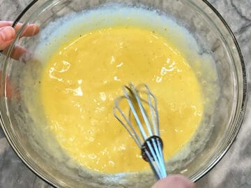 Eggs, sour cream, and spices are mixed in a bowl.