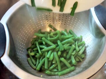 Steamed green beans in a colander.