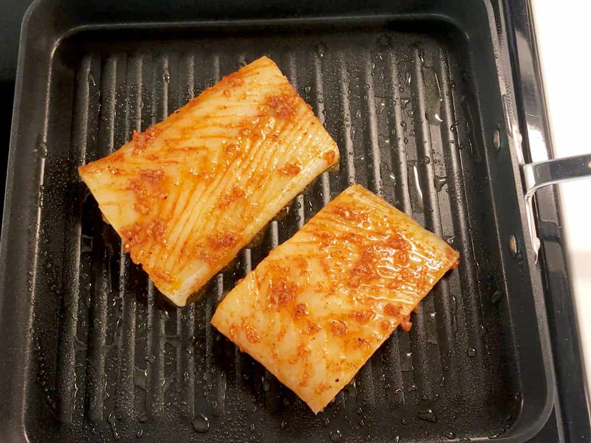 Two halibut fillets in a grill pan.