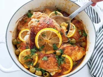 The dish is ready in the saucepan. A serving spoon lifts a piece of chicken up.