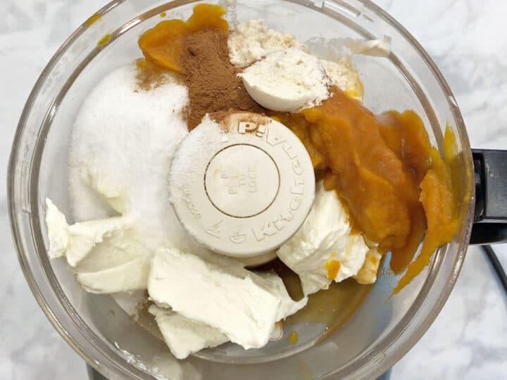 Pumpkin cheesecake ingredients in food processor.