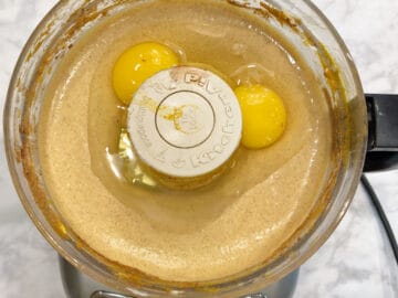 Pumpkin cheesecake ingredients in food processor - adding eggs.