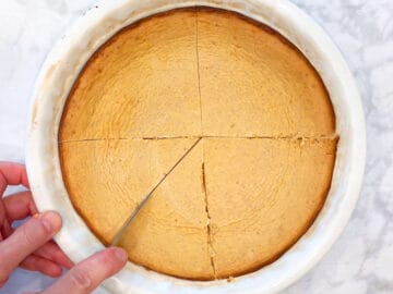 Slicing keto pumpkin cheesecake in the pan.