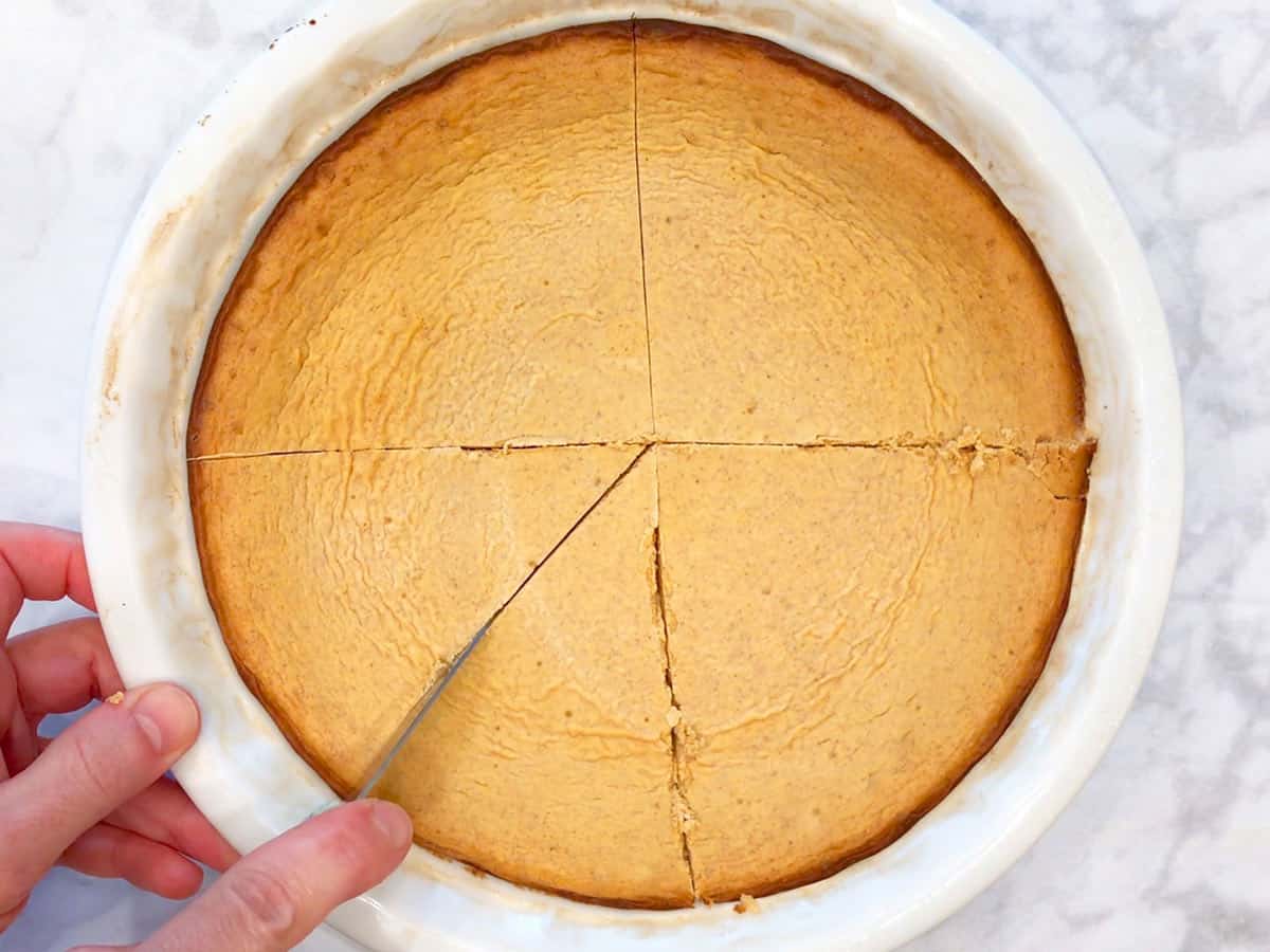 Slicing keto pumpkin cheesecake in the pan.