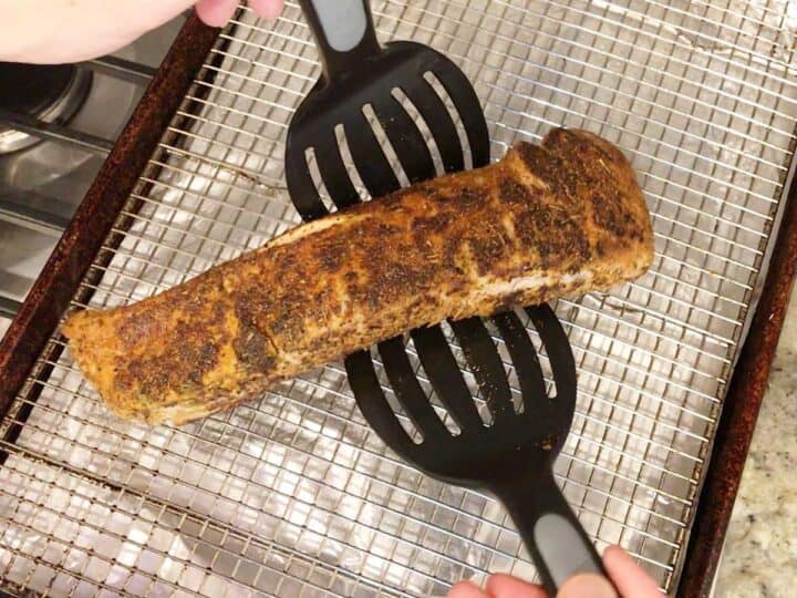 Transferring pork tenderloin to a baking sheet.