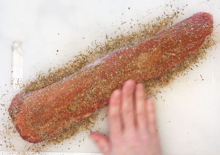 Coating pork tenderloin with spices.