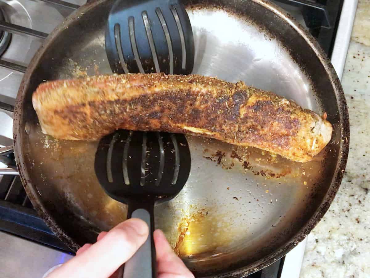Searing pork tenderloin in a skillet.
