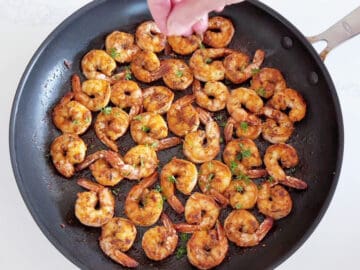 Garnishing sauteed shrimp with parsley.