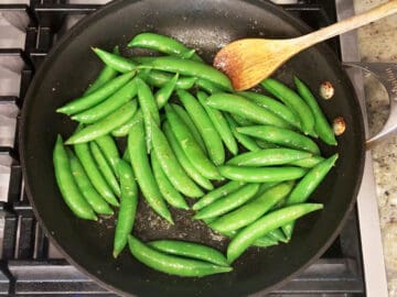 Cooking sugar snap peas in a skillet.