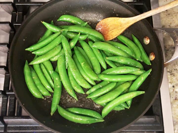 Cooking sugar snap peas in a skillet.