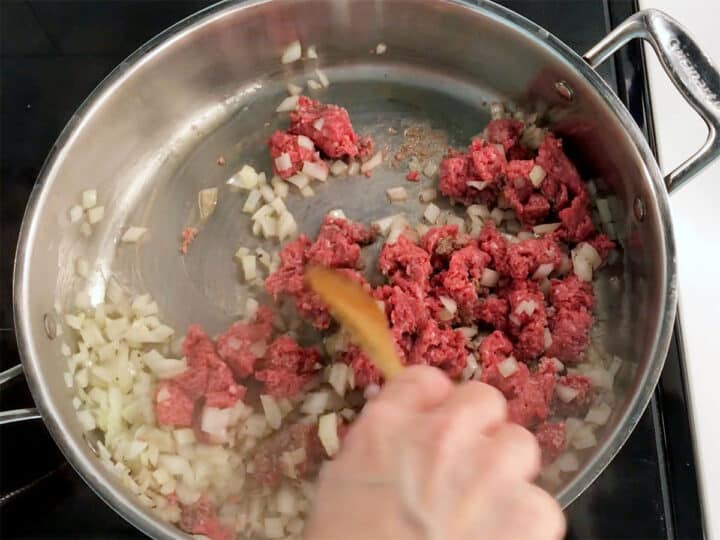 Cooking ground beef and onions in a skillet.