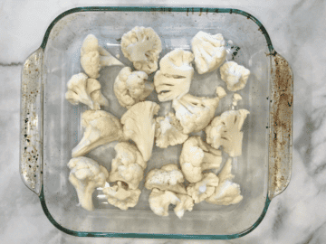 Raw cauliflower florets in a baking dish.