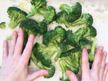 Mixing olive oil into the broccoli.