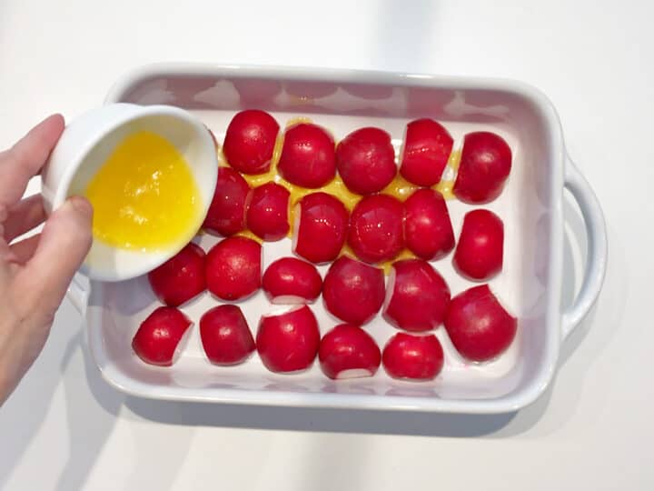 Adding melted butter to pan with radishes.