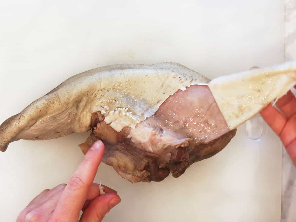 Peeling the skin off cooked beef tongue.