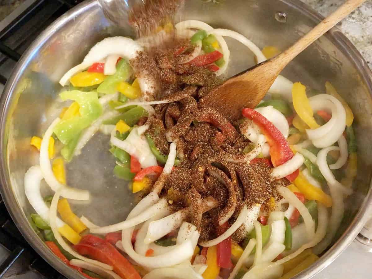 Adding spices to the vegetables in the skillet.