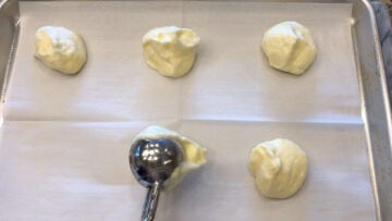 Using a scoop to transfer mounds of the mixture to the baking sheet.