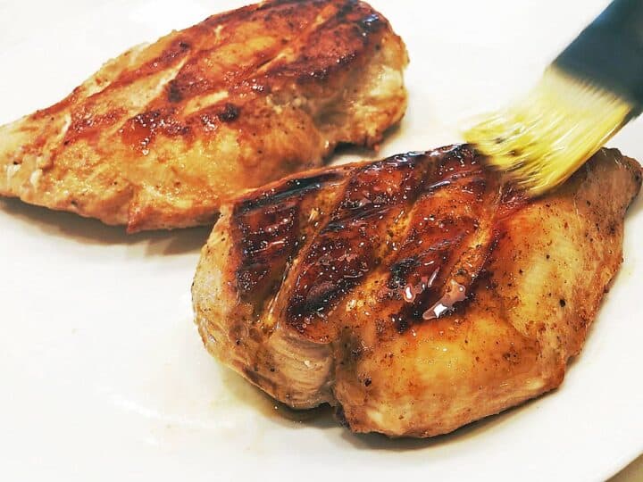 Brushing the grilled chicken with the remaining marinade.