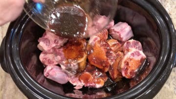 Adding the sauce to the slow cooker pan.