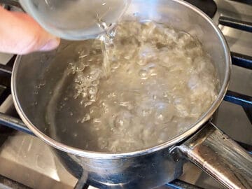 Adding vinegar to the boiling water.