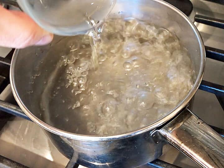 Adding vinegar to the boiling water.