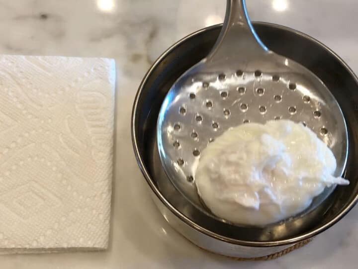Lifting the poached egg from the water.