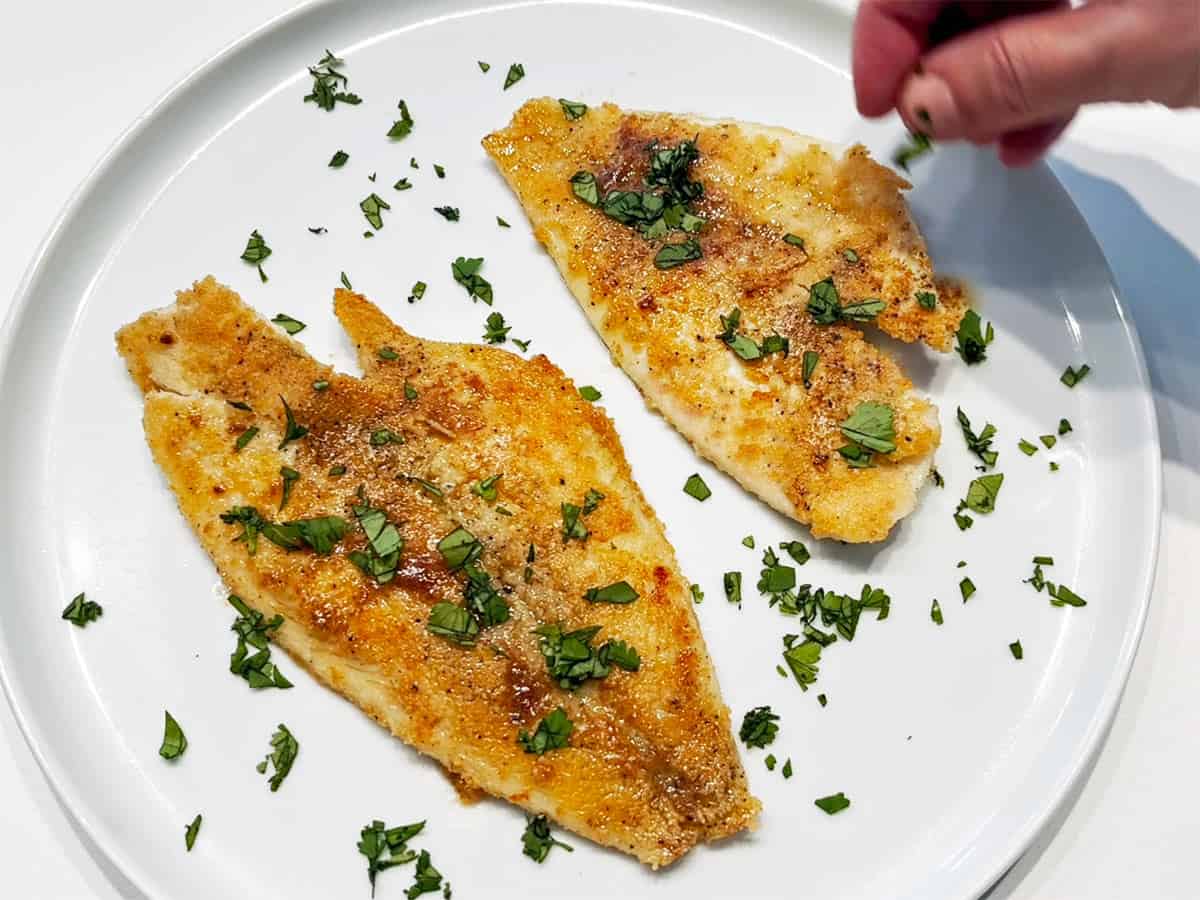 Garnishing the fish with parsley.