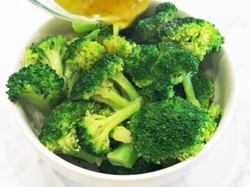 Pouring the dressing on the broccoli.