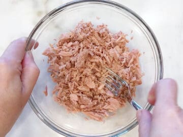 Flaking canned tuna with a fork.