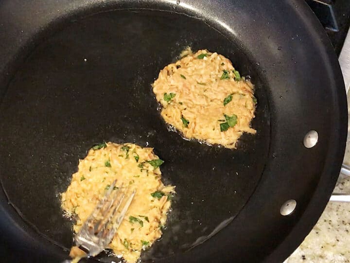 Flattening tuna patties in the skillet.