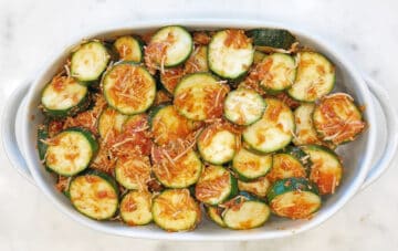 Transferring the coated zucchini to the baking dish.