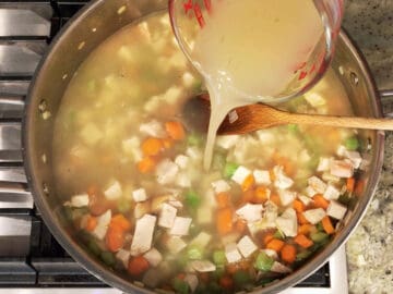 Adding the turkey stock to the saucepan.