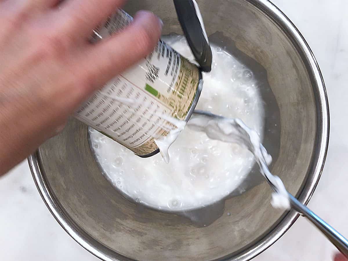 Pouring coconut milk into a bowl.