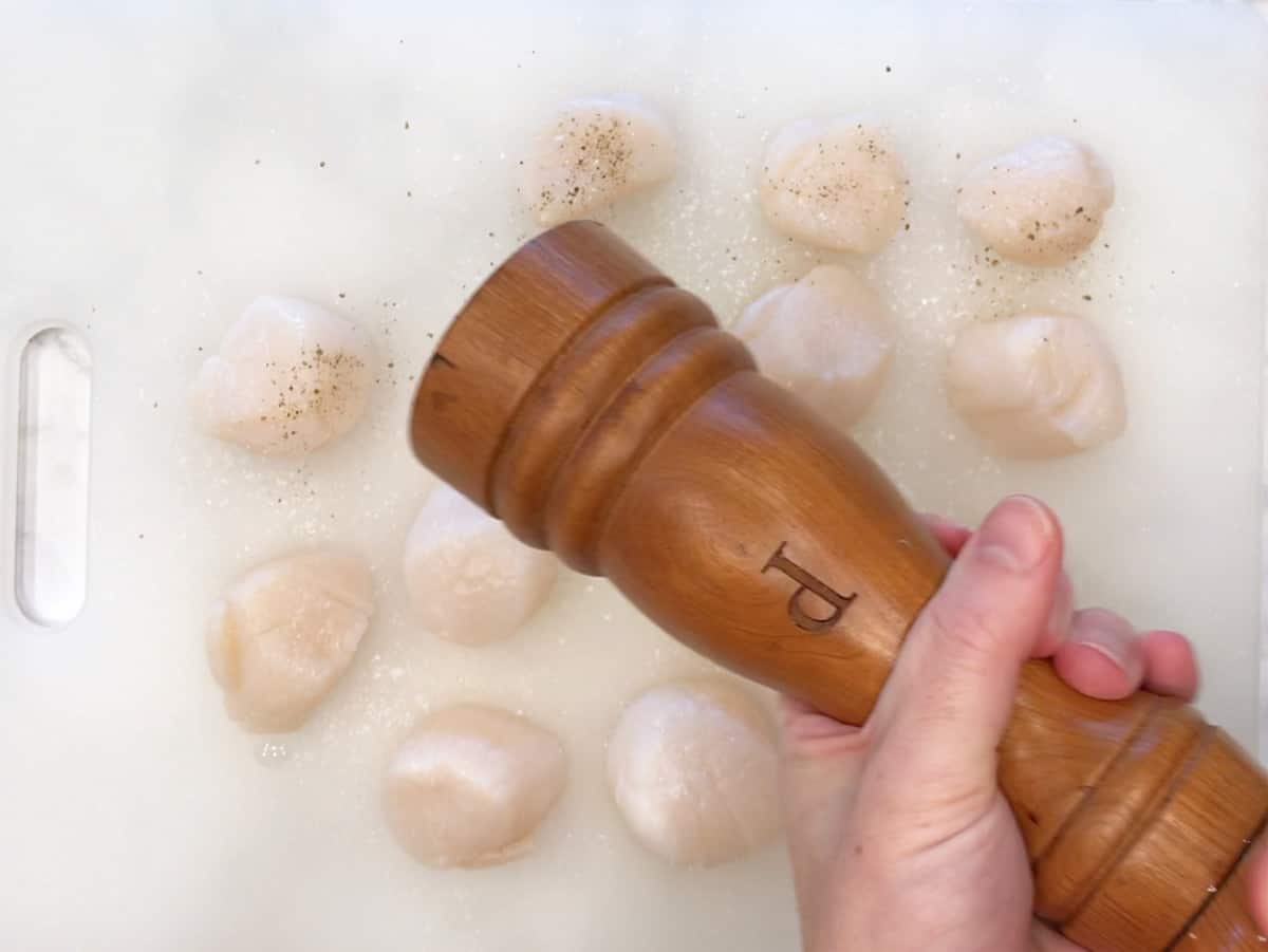 Seasoning the scallops.