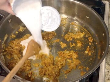 Adding coconut milk to the skillet.