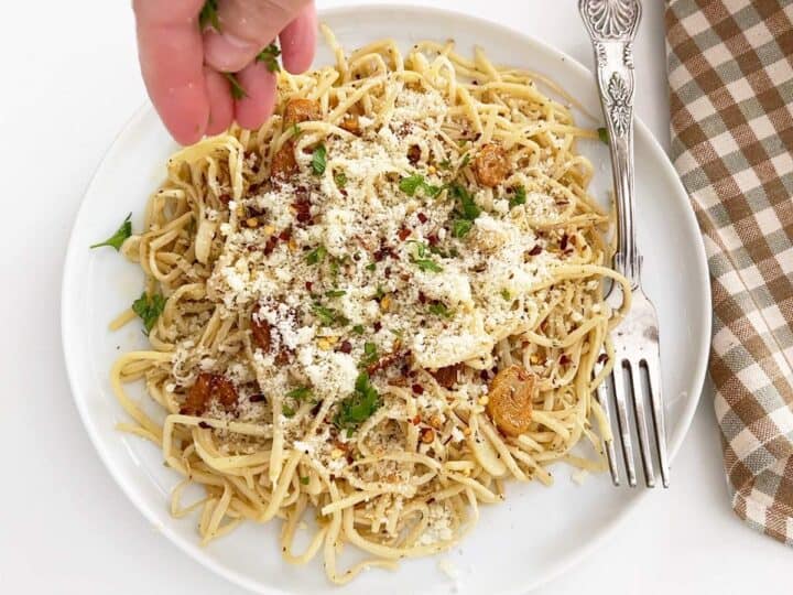 Adding toppings to the cooked pasta.